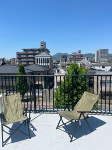 two chairs on a balcony with a view of a city at Ivy Cottage 3F - Vacation STAY 42187v in Kumamoto