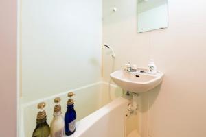 ein Badezimmer mit einem Waschbecken und einer Badewanne mit Flaschen in der Unterkunft IL Regalo Tenjin2 Street Stay in Fukuoka + 25 Fotos