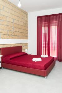 un letto rosso in una stanza con muro di mattoni di ARENARIA B&B ad Avola