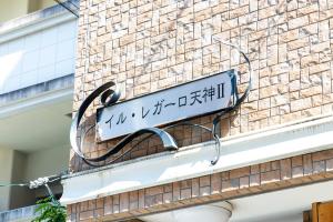 ein Schild an der Seite eines Backsteingebäudes in der Unterkunft IL Regalo Tenjin2 Street Stay in Fukuoka