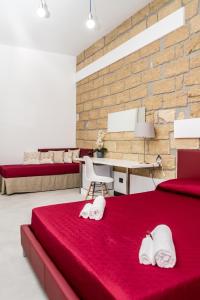 um quarto com duas toalhas brancas numa cama vermelha em ARENARIA B&B em Avola