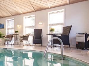 una piscina con sillas, una mesa y ventanas en 12 person holiday home in Pandrup-By Traum, en Rødhus