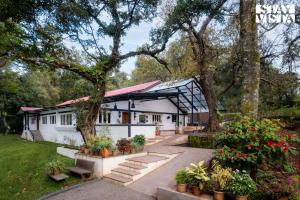 une maison blanche avec un arbre et quelques plantes dans l'établissement StayVista at The Floramer with Bonfire, Lawn, à Panchgani