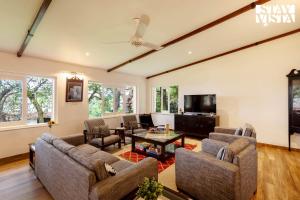 un salon avec deux canapés et une télévision dans l'établissement StayVista at The Floramer with Bonfire, Lawn, à Panchgani