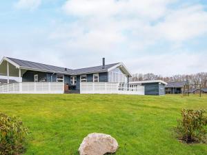 a house with a white fence on a green field at 6 person holiday home in Sydals in Sarup