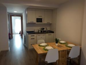 uma cozinha com uma mesa de madeira e cadeiras brancas em Apartamentos Jurramendi - Los Arcos em Los Arcos
