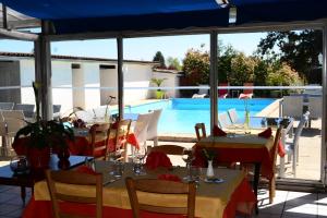 un restaurant avec des tables et des chaises ainsi qu'une piscine dans l'établissement La Maison Blanche, à Romanèche-Thorins