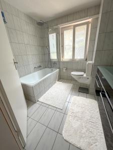 a white bathroom with a tub and a toilet at Room in Homestay with amazing view of lake - Zimmer in einer Gastfamilie mit herrlichem Blick auf den See in Feusisberg