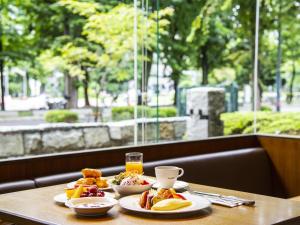 a table with two plates of food and a glass of orange juice at Sapporo View Hotel Odori Park in Sapporo