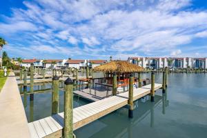 a dock with a hut on the water with houses at Cambria Hotel St Petersburg-Madeira Beach Marina in St Pete Beach