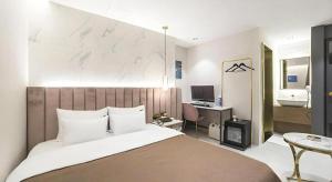 a bedroom with a large bed with a desk and a bathroom at Den Basta Hotel bifc in Busan +163 photos