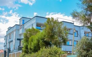 a blue building with trees in front of it at Kevara by H&D Stays in Nanyuki