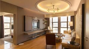 een woonkamer met een witte bank en een tv bij Clear Lake Hotel in Shanwei