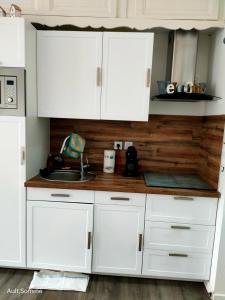 a kitchen with white cabinets and a sink at La parenthèse in Ault +1 photo