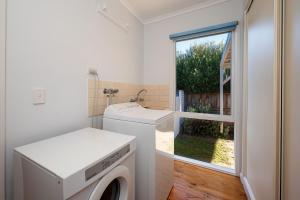 a laundry room with a washing machine and a window at Hilltop Cottage - Beachside Escape with Fireplace in Blairgowrie