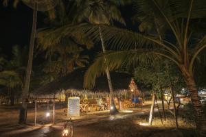 un ristorante di notte con palme e luci di Marari Beach Resort a Mararikulam Altre 22 foto