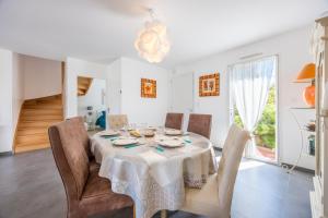 a white dining room with a table and chairs at La Maison du Payré - proche plages in Talmont-Saint-Hilaire