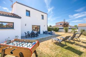 a backyard with a ping pong table and chairs at La Maison du Payré - proche plages in Talmont-Saint-Hilaire