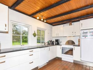 a kitchen with white cabinets and a wooden ceiling at 6 person holiday home in Bindslev in Bindslev