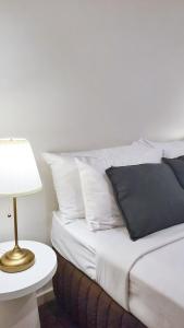a bed with white pillows and a table with a lamp at Park Avenue - Carnegie in Carnegie +31 photos
