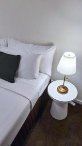 a bed with white pillows and a table with a lamp at Park Avenue - Carnegie in Carnegie