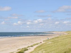 a beach with people on the sand and the ocean at Cozy Retreat by the Sea - By Traum Ferienwohnungen in Hvide Sande