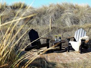 two chairs and a table in front of some tall grass at Cozy Retreat by the Sea - By Traum Ferienwohnungen in Hvide Sande