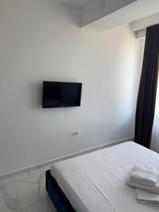 a bedroom with a bed and a flat screen tv on the wall at Virgo Apartaments Summer Land in Mamaia +115 photos