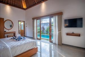 - une chambre avec un lit, une télévision et une piscine dans l'établissement Villa di carik ubud, à Ubud