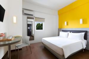 a bedroom with a white bed and a desk and a table at Amaris Hotel Padjajaran Bogor in Bogor +113 photos