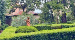 a woman is walking through a garden with bushes at Casa vacanze Mirage in Bergamo