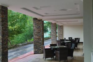 a dining room with tables and chairs and a large window at Nizalia Hotel by Marvelous Holidays in Patriata