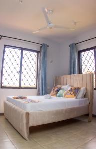 1 cama grande en un dormitorio con 2 ventanas en Baobab Oceanline Residence, en Mombasa