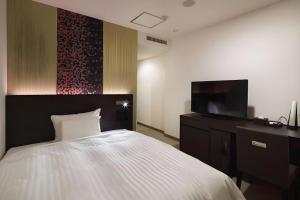 a bedroom with a bed and a flat screen tv at JR-EAST HOTEL METS NAGAOKA in Nagaoka