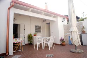 une terrasse avec une table et des chaises blanches ainsi qu'une maison blanche dans l'établissement Casa Dei Furnari, à Collepasso