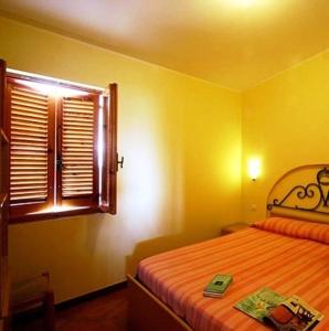 una camera gialla con letto e finestra di Residence Villaggio Smedile a Capo Vaticano