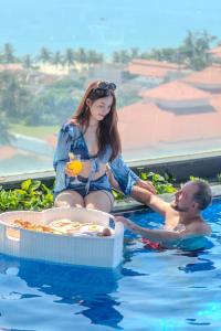 a man and a woman in a swimming pool at Sea Phoenix Hotel Da Nang in Danang