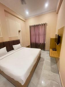 1 dormitorio con cama blanca grande y cortina en Hotel The Taj Incredible Agra, en Agra
