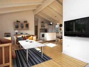a living room with a couch and a table and a tv at Tranquil Haven in Nr Lyngby-By Traum in Løkken
