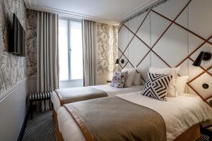 a hotel room with two beds and a window at Hôtel Jardin Le Bréa in Paris