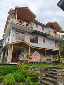 a large house with a balcony and some chairs at Shasha in Manāli