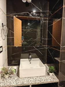 a bathroom with a white sink and black tiles at Shasha in Manāli +40 photos