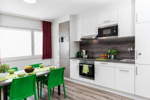 a kitchen with white cabinets and a table with green chairs at Business and Family Homes in Burgau