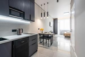 a kitchen with black and white cabinets and a table at Квартира в стиле лофт in Almaty