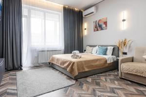 a bedroom with a bed and a chair and a window at Квартира в стиле лофт in Almaty