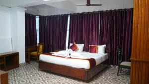 a bedroom with a large bed with purple curtains at Pournami Inn in Chengannūr