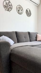 a gray couch in a living room with plates on the wall at Apartman SLAVONIA 4 in Đakovo
