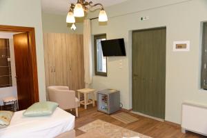 a bedroom with a bed and a tv and a door at Alexandra Hotel in Kaléntzion