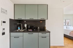 a kitchen with white cabinets and a bed in a room at Limehome Vienna Hietzinger Hauptstraße in Vienna +40 photos