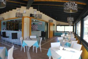 un restaurante con mesas y sillas blancas y un bar en Le Vanille en Costa Rei